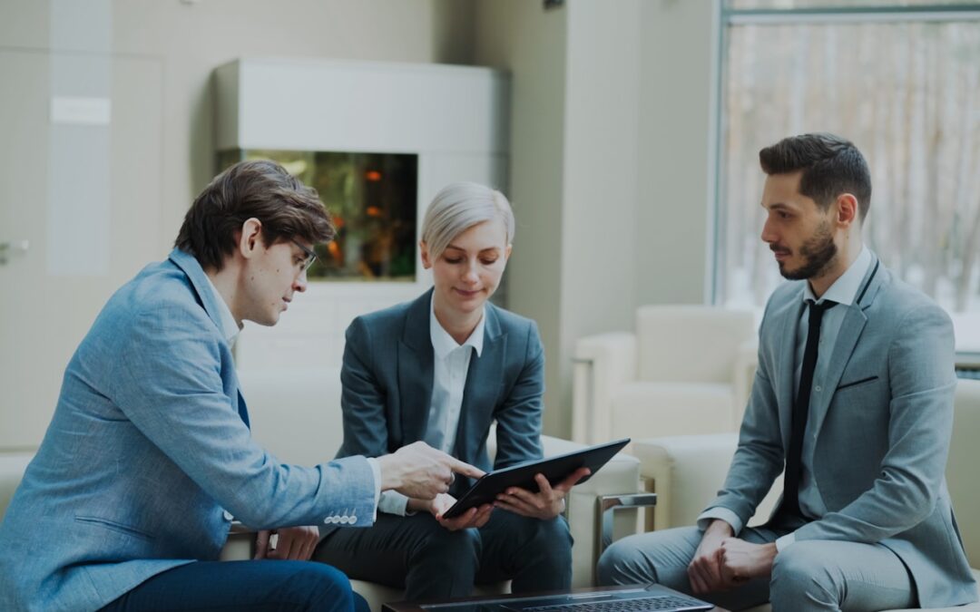 Three professionals discussing a tablet in a modern office