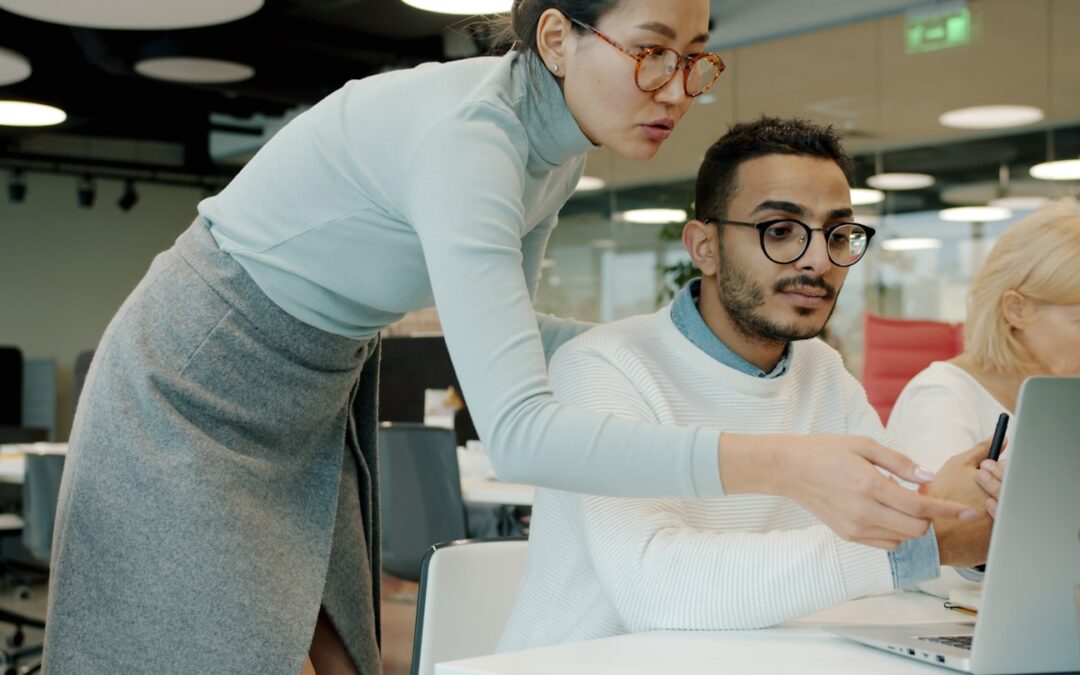 Two colleagues collaborating on a laptop in office