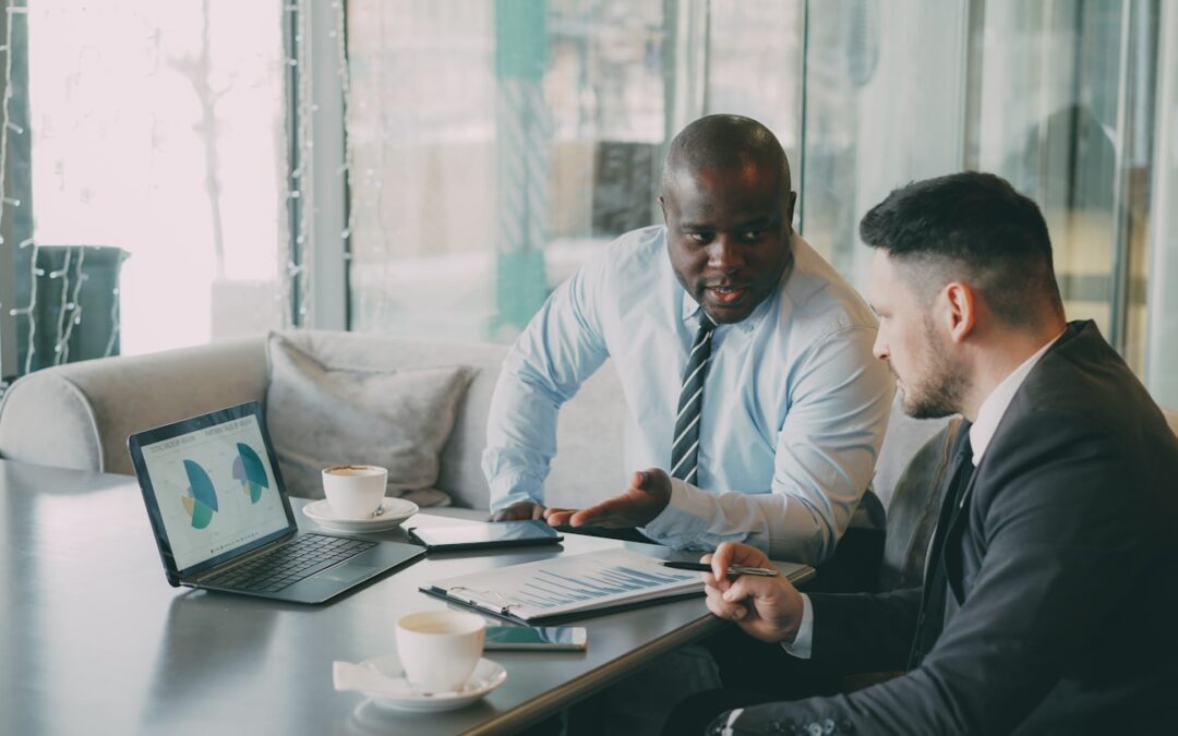 Two businessmen discussing charts on a laptop
