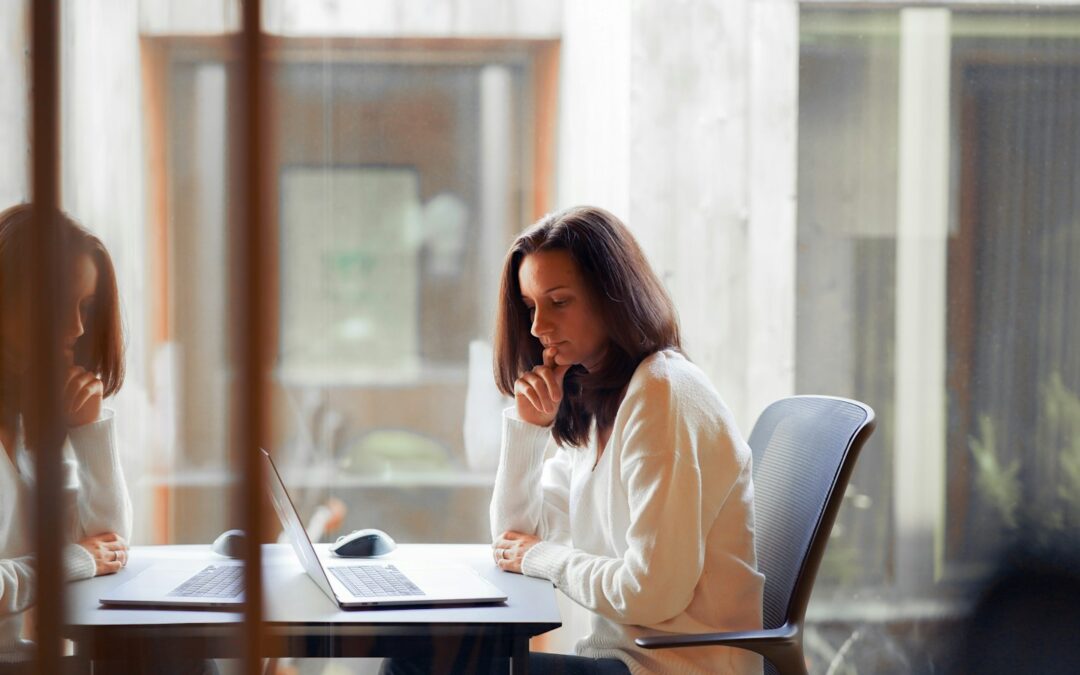 a woman sitting at a table with a laptop computer